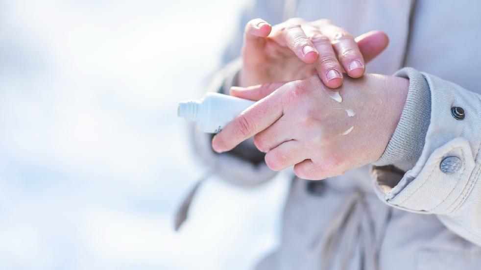 woman putting on hand cream in winter